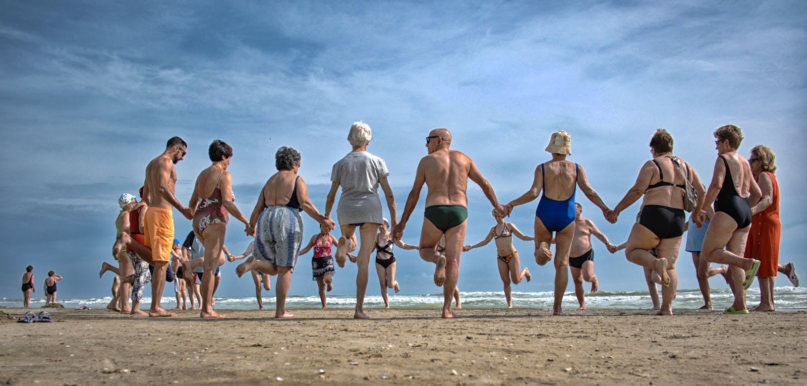 A joyful group of older adults laughing together at the beach